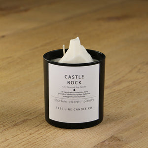 A white soy wax replica candle of  Castle Rock in a round, black glass.