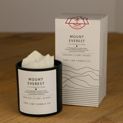 A white wax replica candle of Mount Everest next to a white box with red and black lettering.