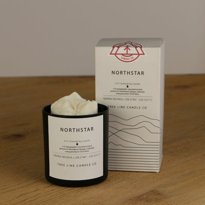 A white wax replica candle of Northstar summit next to a white box with red and black lettering