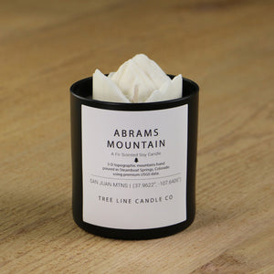  A white soy wax replica candle of Abrams Mountain in a round, black glass.