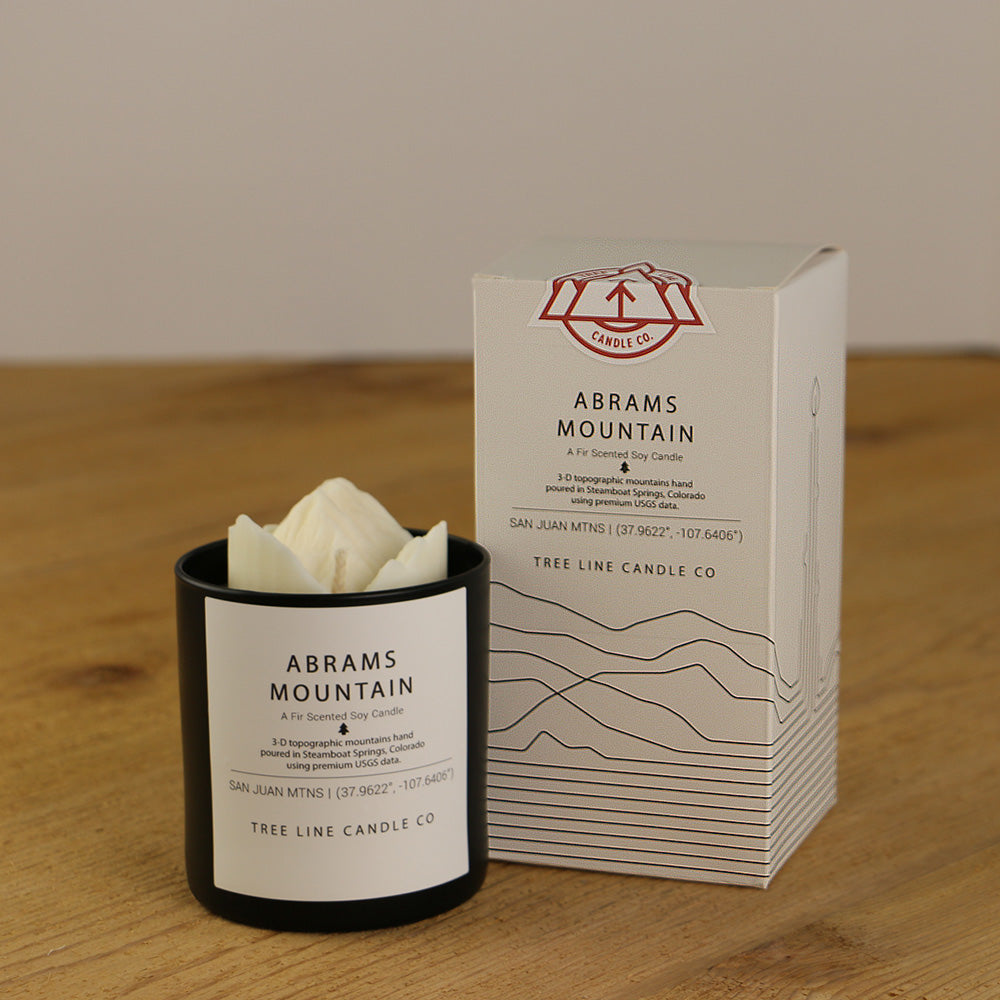A white wax replica candle of Abrams Mountain next to a white box with red and black lettering.