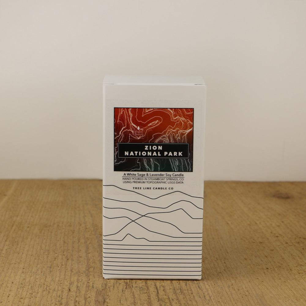 A white box with an orange, red and green label with topography lines by Tree Line Candle Co.