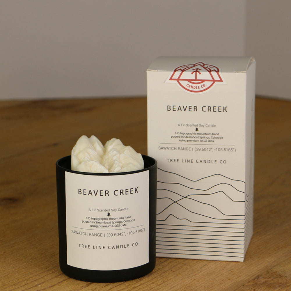 A white wax replica candle of Beaver Creek next to a white box with red and black lettering.