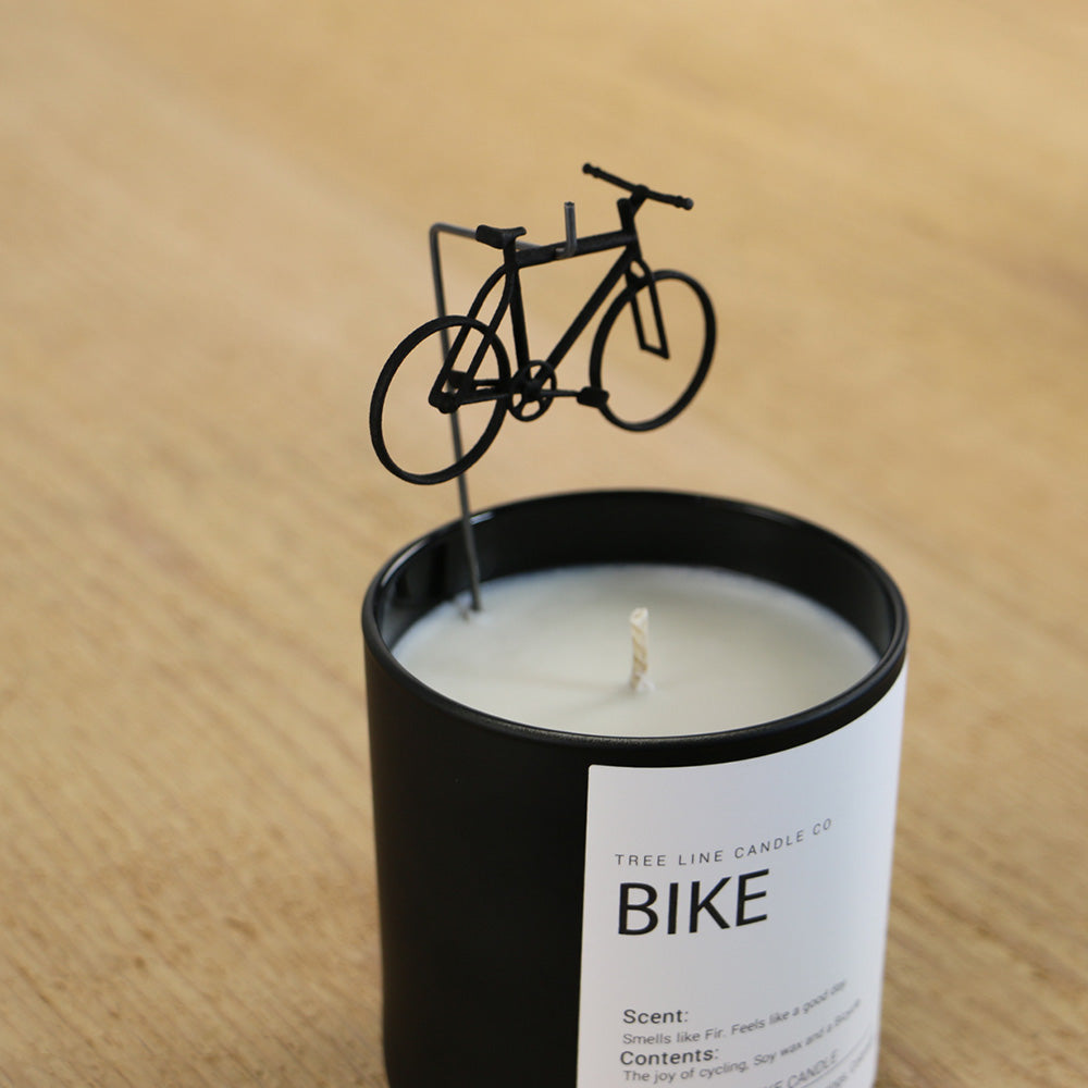 A close view of Bike candle that has a small black bicycle placed over it.