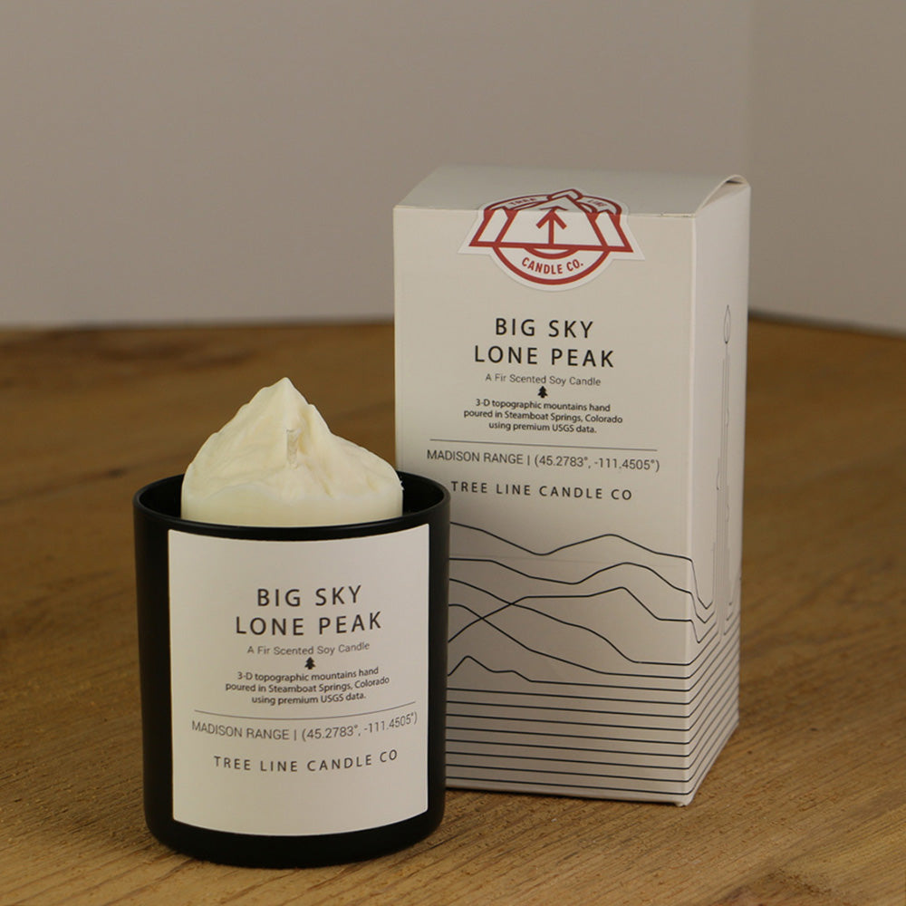 A white wax replica candle of Big Sky Lone Peak next to a white box with red and black lettering.