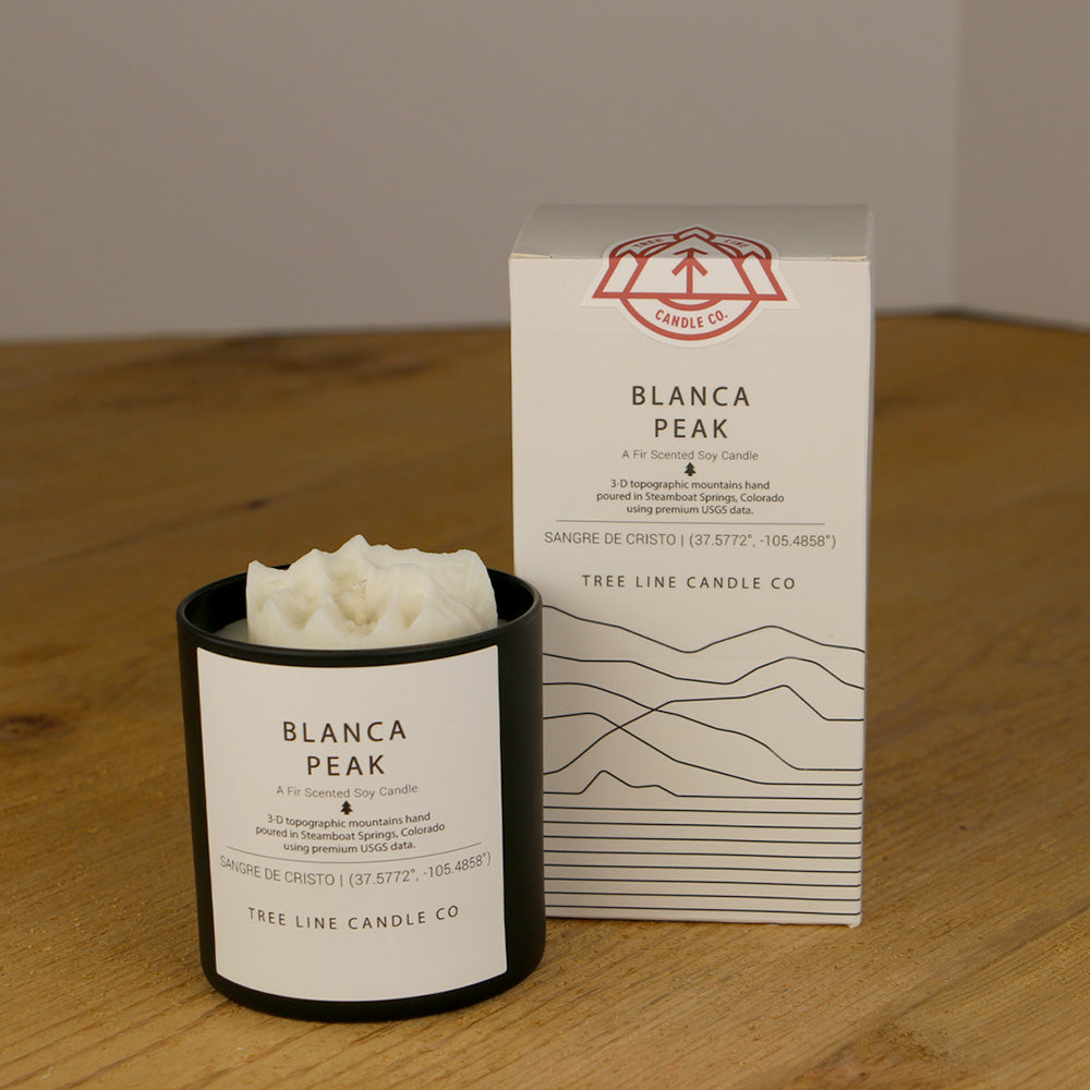A white wax replica candle of Blanca Peak next to a white box with red and black lettering.
