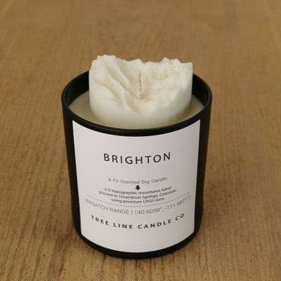  A white soy wax replica candle of Brighton mountain in a round, black glass.