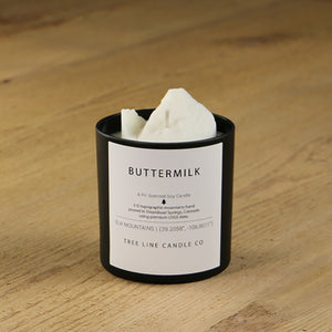 A white soy wax replica candle of Buttermilk mountain in a round, black glass.