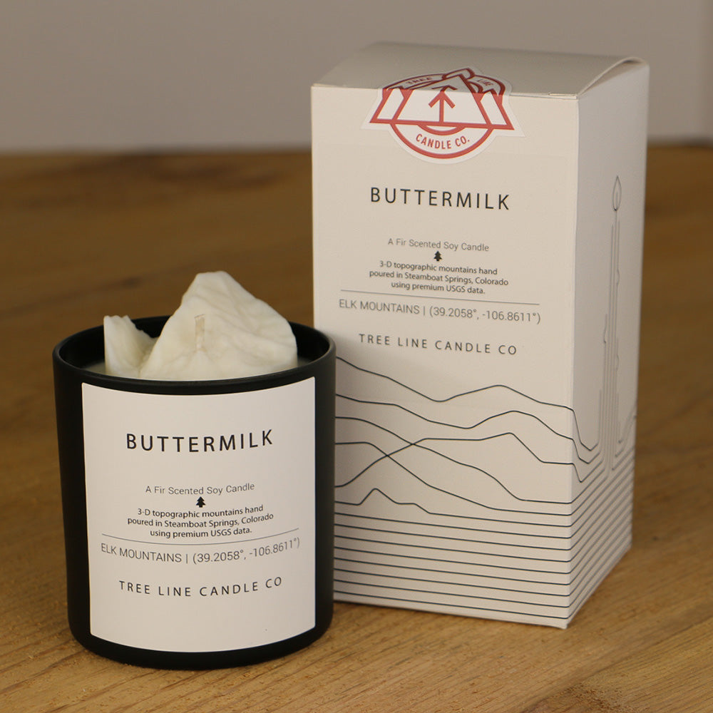 A white wax replica candle of Buttermilk summit next to a white box with red and black lettering.