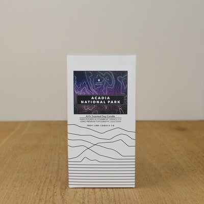 A white box with a purple and black label with topography lines by Tree Line Candle Co.