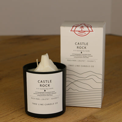 A white wax replica candle of Castle Rock next to a white box with red and black lettering.