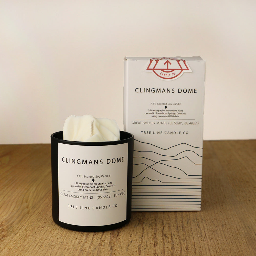 A white wax candle named Clingmans Dome is next to a white box with red and black lettering.