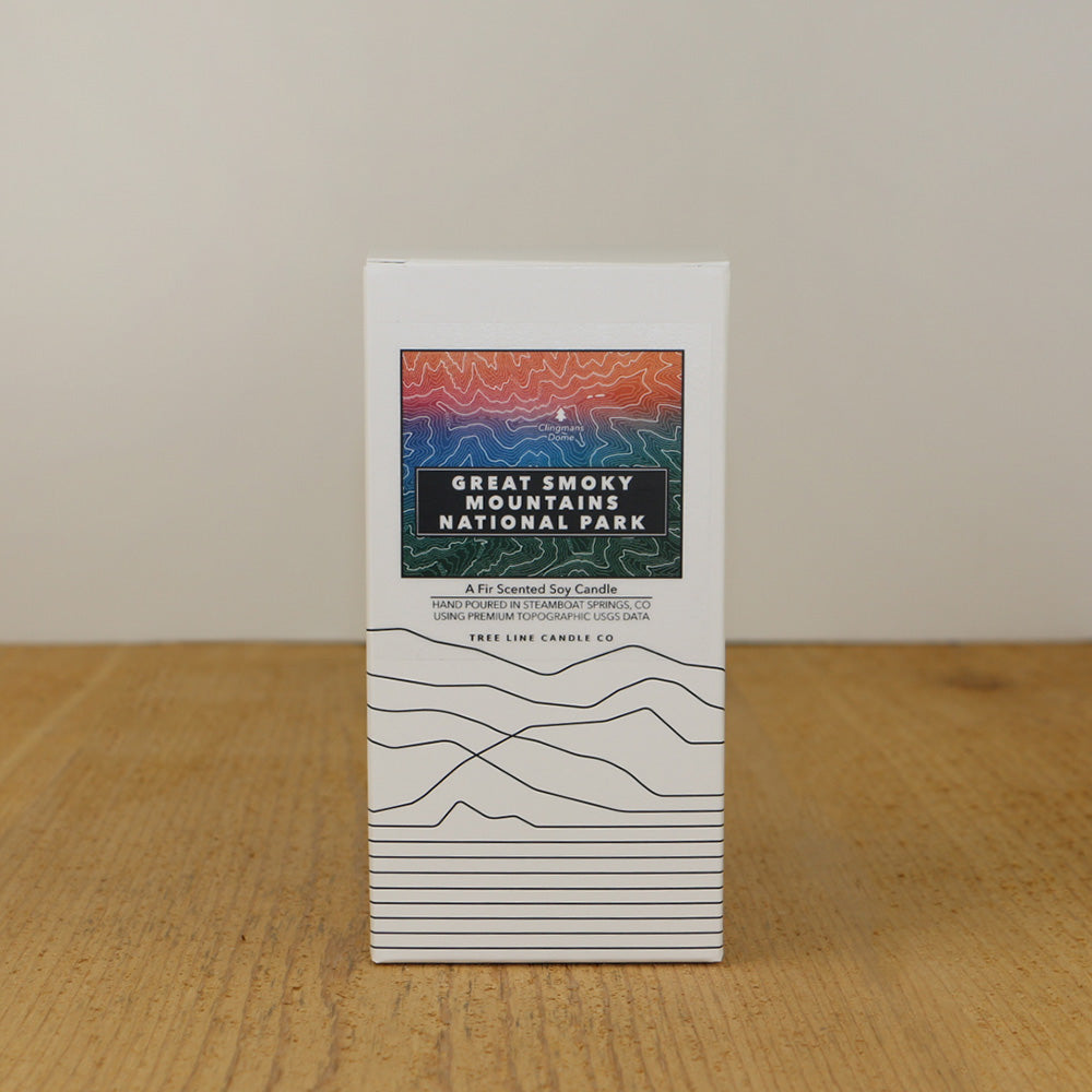 A white box with an orange, red, blue and green label with topography lines by Tree Line Candle Co.