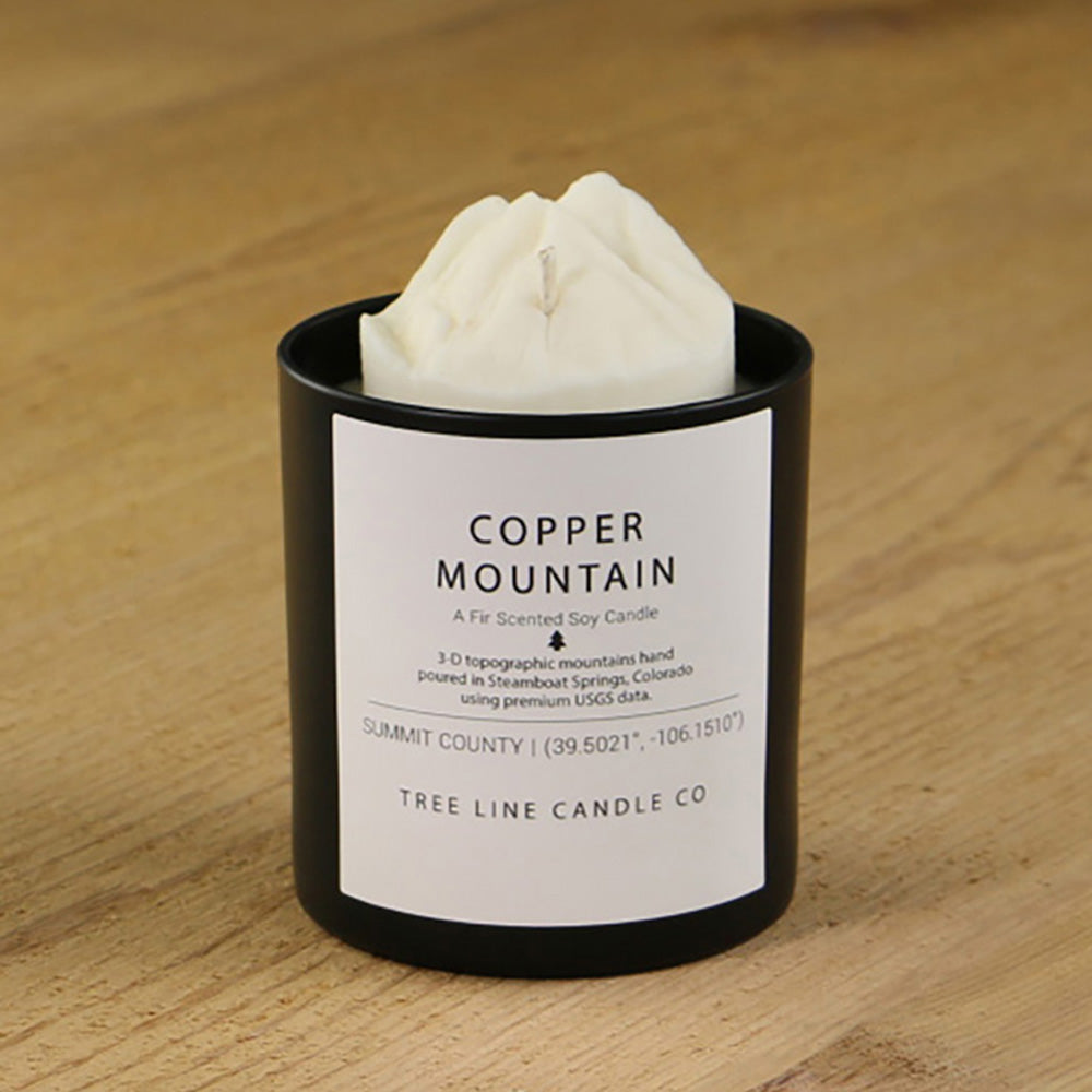 A white soy wax replica candle of Copper Mountain in a round, black glass.