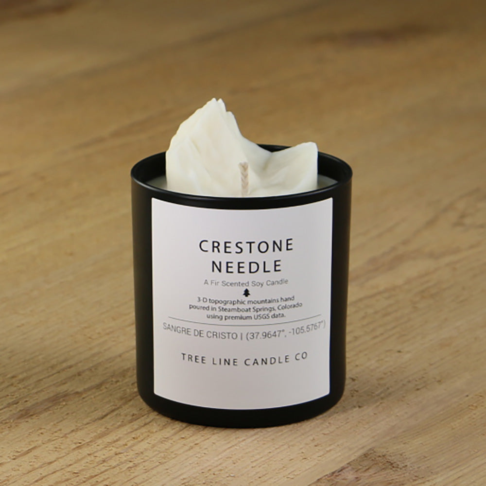  A white soy wax replica candle of Crestone Needle in a round, black glass.