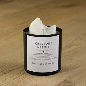  A white soy wax replica candle of Crestone Needle in a round, black glass.