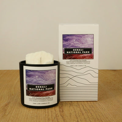 A white wax candle named Denali is next to a white box with red and black lettering.