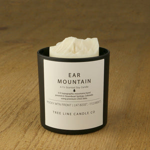  A white soy wax replica candle of Ear Mountain in a round, black glass.
