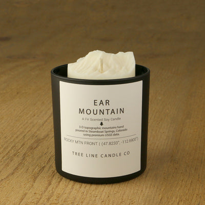  A white soy wax replica candle of Ear Mountain in a round, black glass.