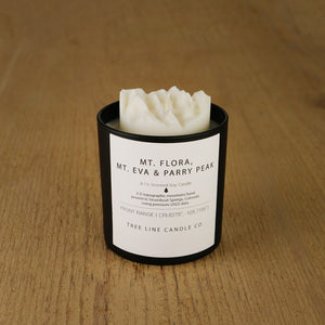 A white soy wax replica candle of Mt. Flora, Mt. Eva & Parry Peak in a round, black glass.