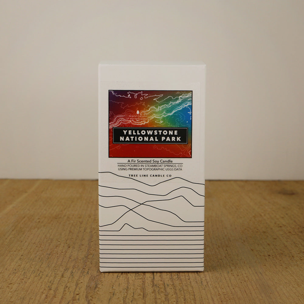 A white box with an orange, blue and green label with topography lines by Tree Line Candle Co.