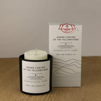 A white wax candle named Grand Canyon is next to a white box with red and black lettering.