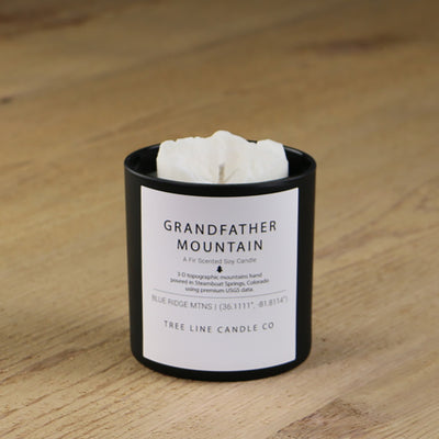  A white soy wax replica candle of Grandfather Mountain in a round, black glass.