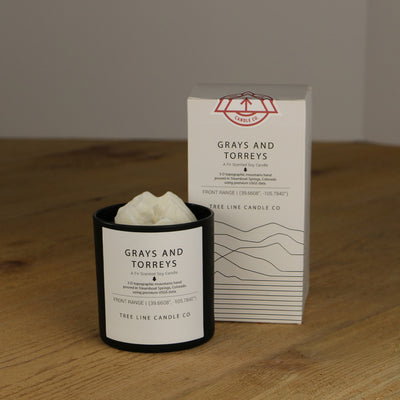 A white wax replica candle of Grays and Torreys next to a white box with red and black lettering.