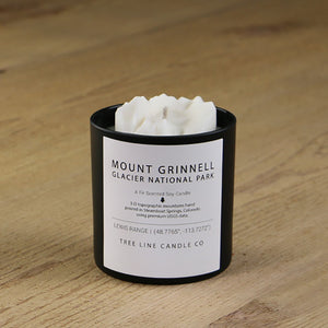 A white soy wax replica candle of Mount Grinnell Glacier National Park  in a round, black glass.