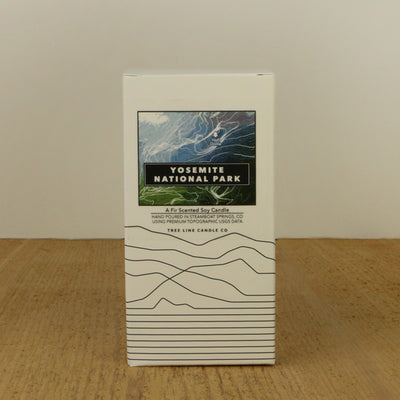 A white box with a blue, black and green label with topography lines by Tree Line Candle Co.