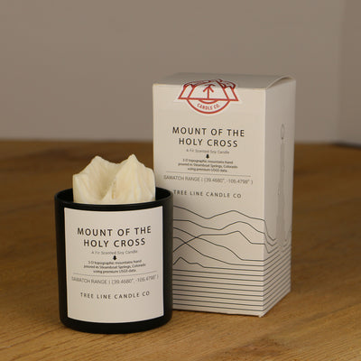 A white wax replica candle of Mount Of The Holy Cross summit next to a white box with red and black lettering.