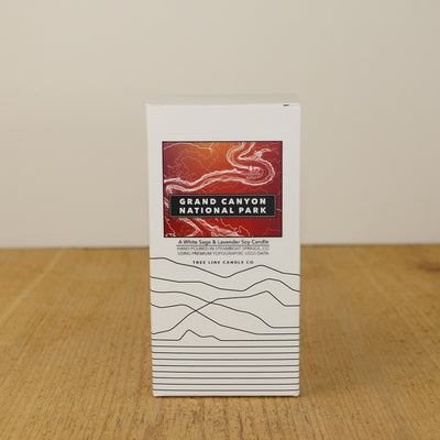 A white box with a red and orange label with topography lines by Tree Line Candle Co.