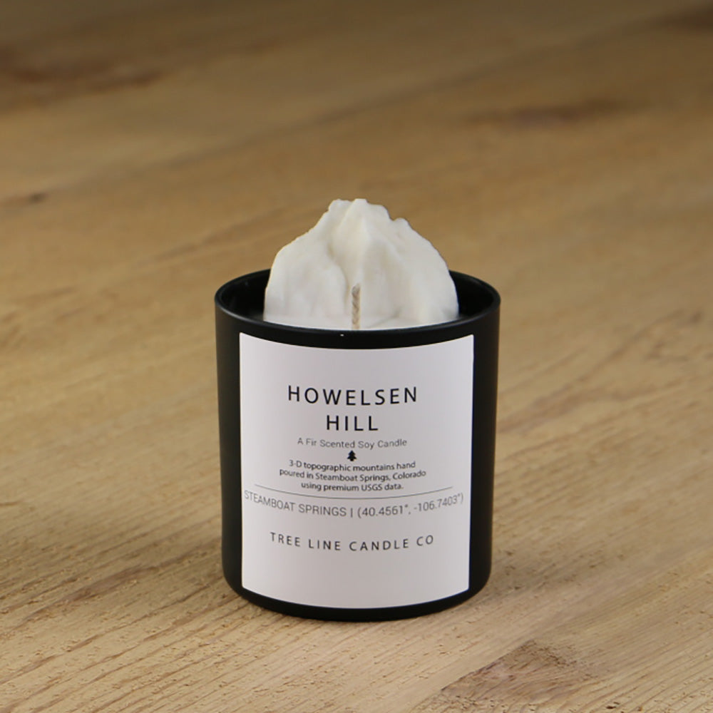  A white soy wax replica candle of Howelsen Hill in a round, black glass.