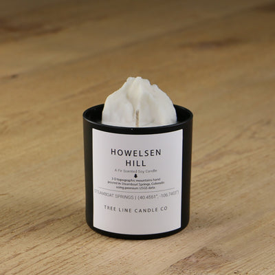  A white soy wax replica candle of Howelsen Hill in a round, black glass.