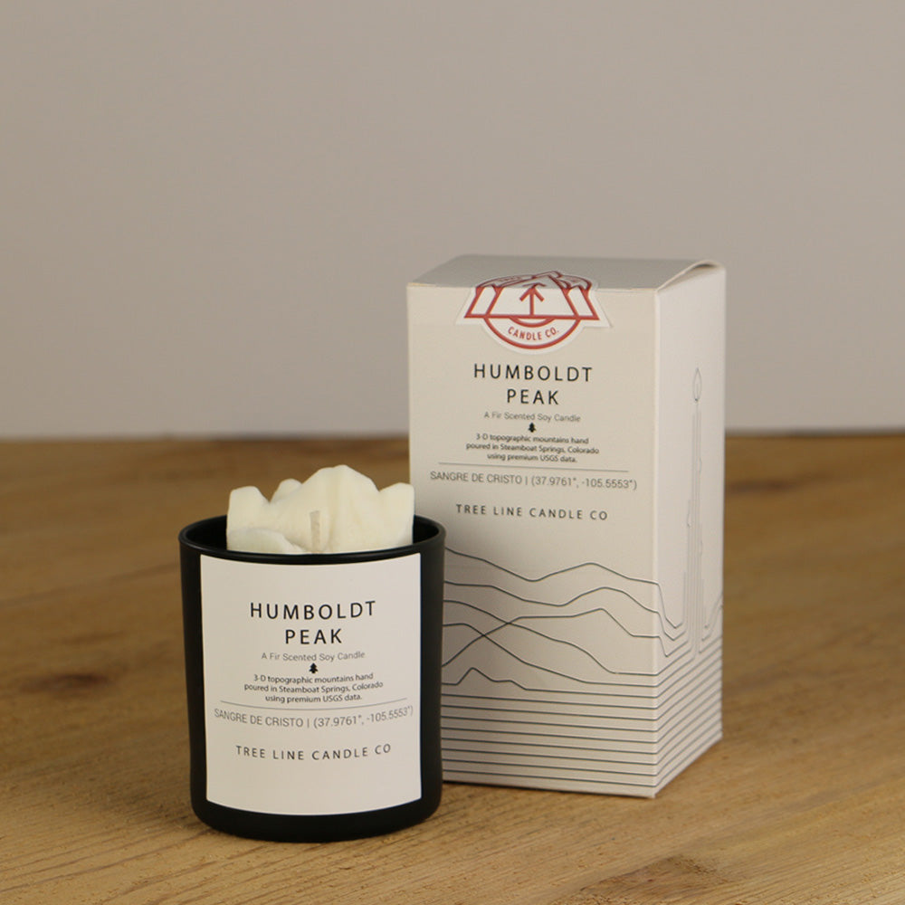 A white wax replica candle of Humboldt Peak next to a white box with red and black lettering.