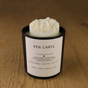  A white soy wax replica candle of Ken Caryl in a round, black glass.