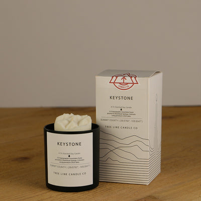 A white wax replica candle of Keystone mountain next to a white box with red and black lettering.