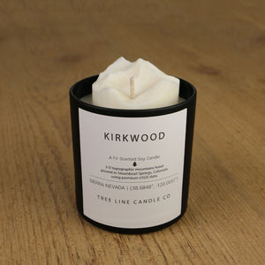  A white soy wax replica candle of Kirkwood in a round, black glass.