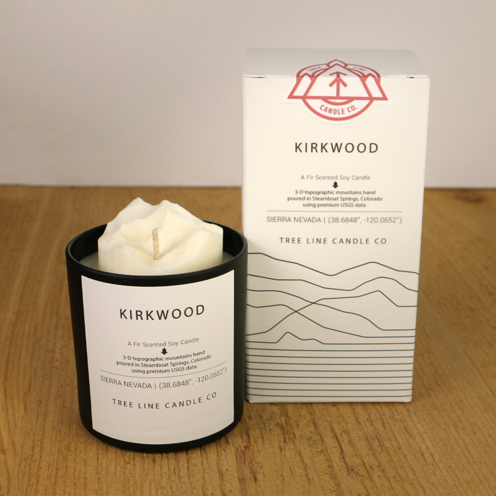 A white wax candle named Kirkwood is next to a white box with red and black lettering.