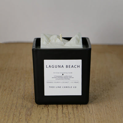  A white soy wax replica candle of Laguna Beach in a square, black glass.