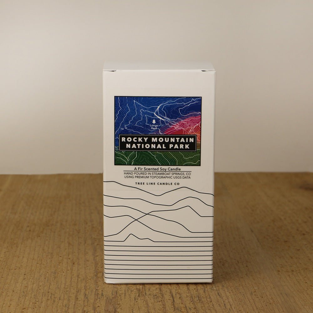 A white box with a blue, red and green label with topography lines by Tree Line Candle Co.