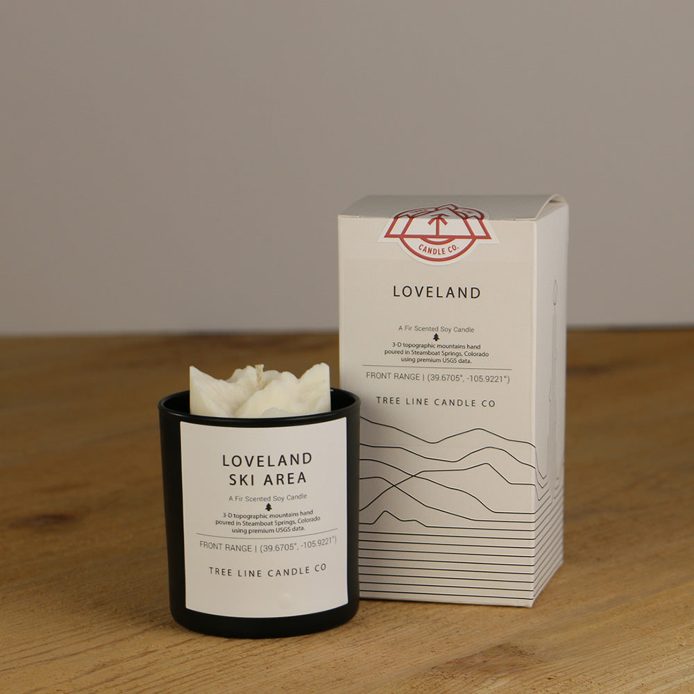 A white wax replica candle of Loveland Ski Area next to a white box with red and black lettering.