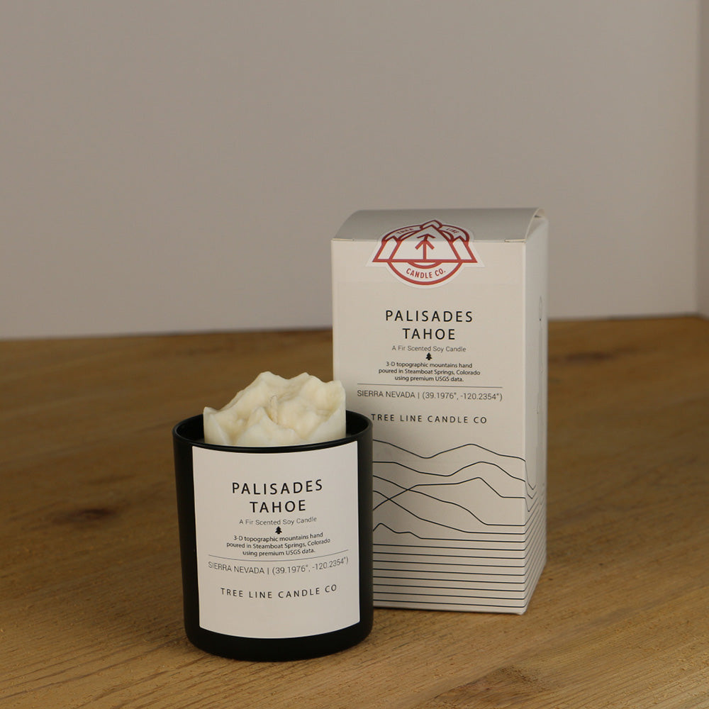A white wax replica candle of Palisades Tahoe next to a white box with red and black lettering.