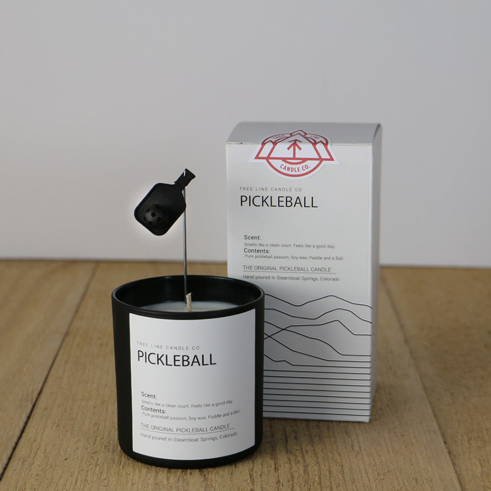 A white wax candle named Pickleball is next to a white box with red and black lettering.