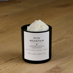A white soy wax replica candle of Pico Mountain in a round, black glass.