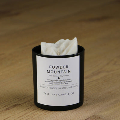 A white soy wax replica candle of Powder Mountain in a round, black glass.
