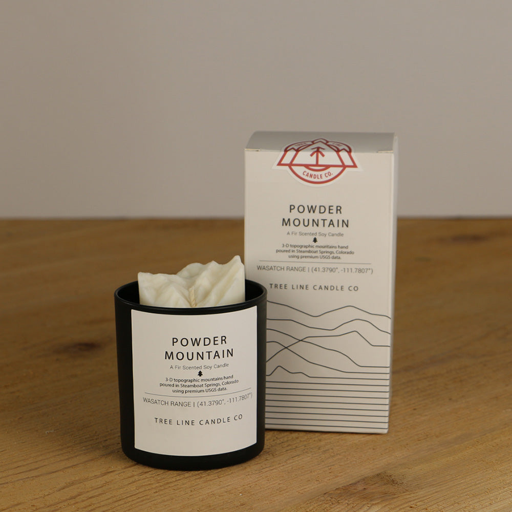 A white wax replica candle of Powder Mountain next to a white box with red and black lettering.