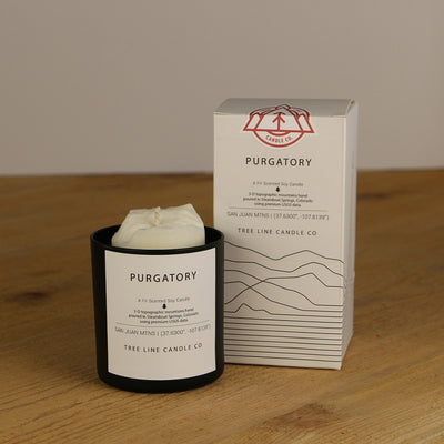 A white wax replica candle of Purgatory summit next to a white box with red and black lettering.