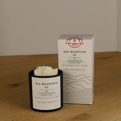 A white wax replica candle of Red Mountain #3 next to a white box with red and black lettering.