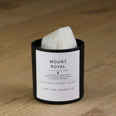 A white soy wax replica candle of Mount Royal in a round, black glass.